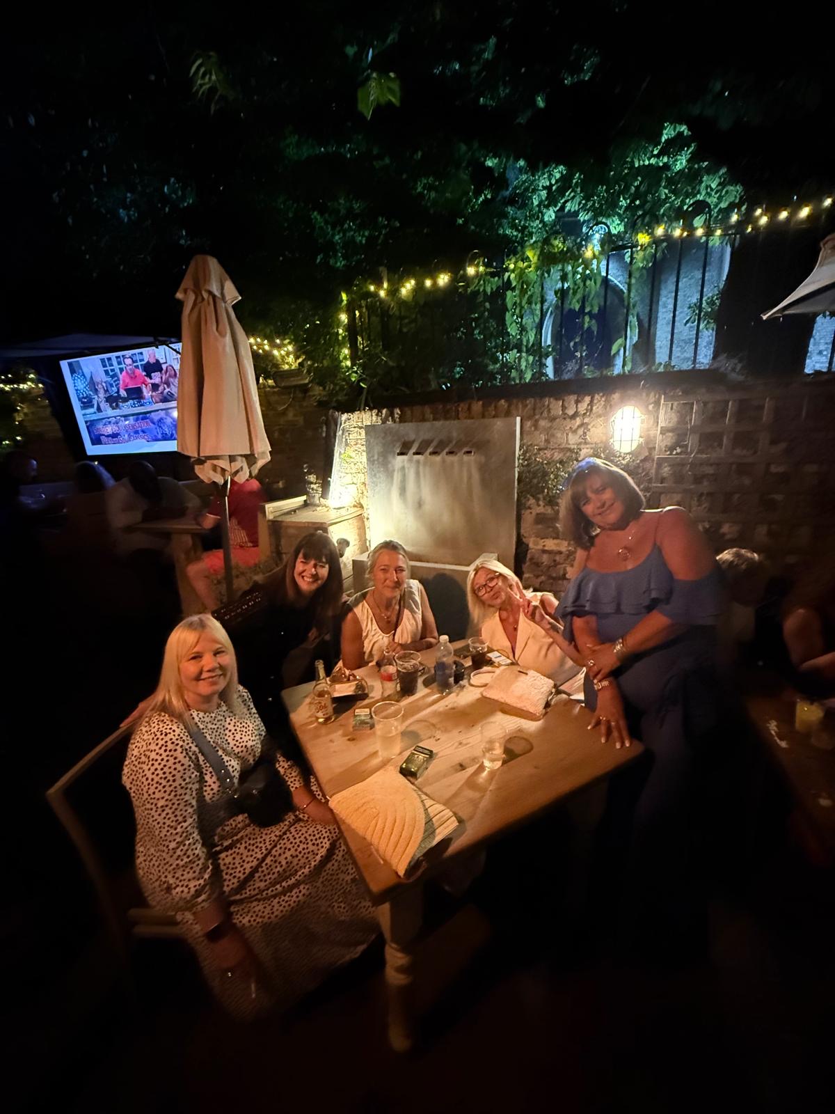 A group of friends celebrating at a garden table at The Bell Inn