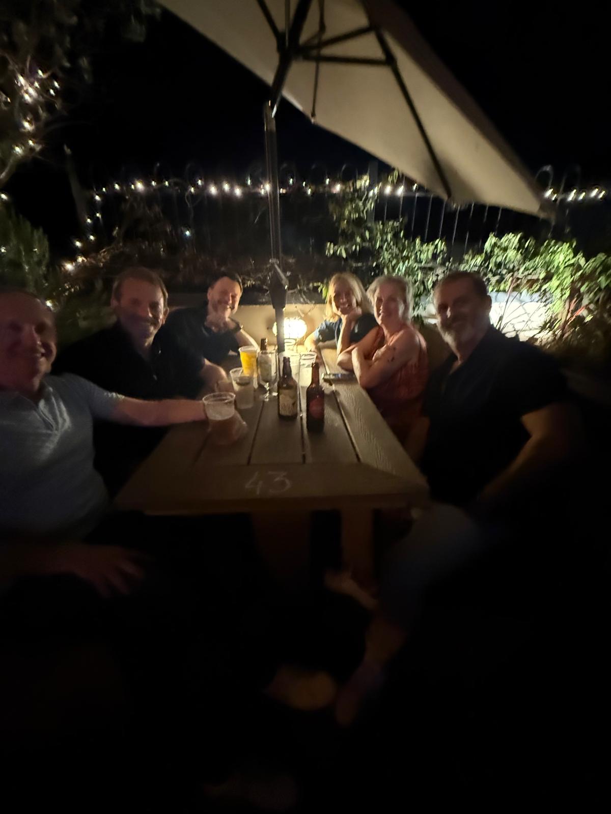 Friends gathered around a long table under a parasol at The Bell Inn