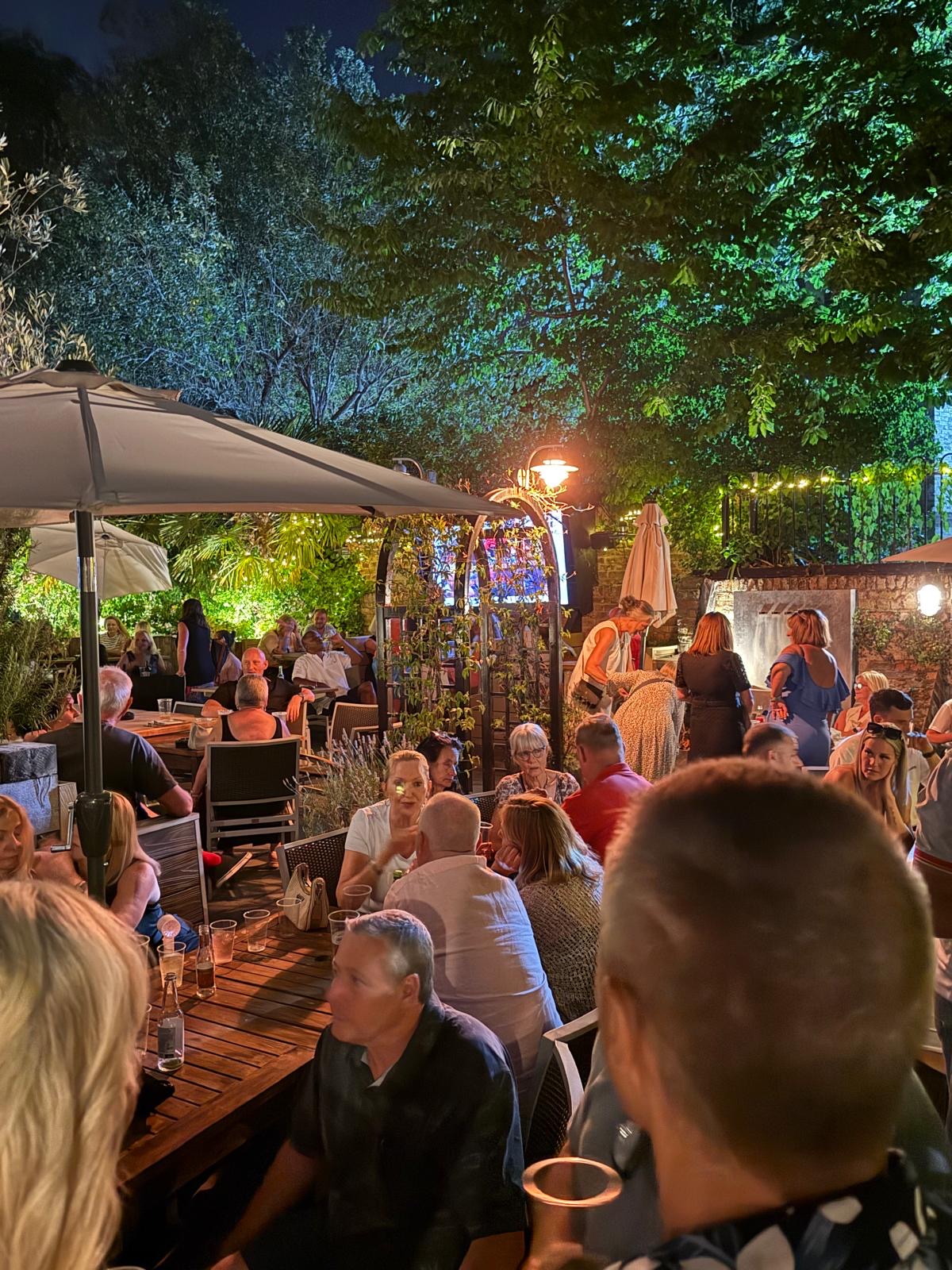 Two guests laughing over drinks in the courtyard at The Bell Inn